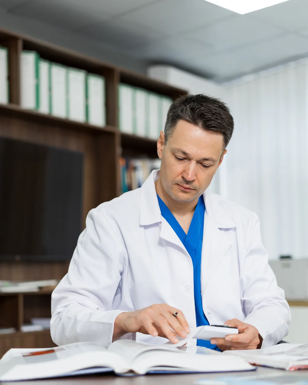 Médico estuda literatura médica à mesa do consultório